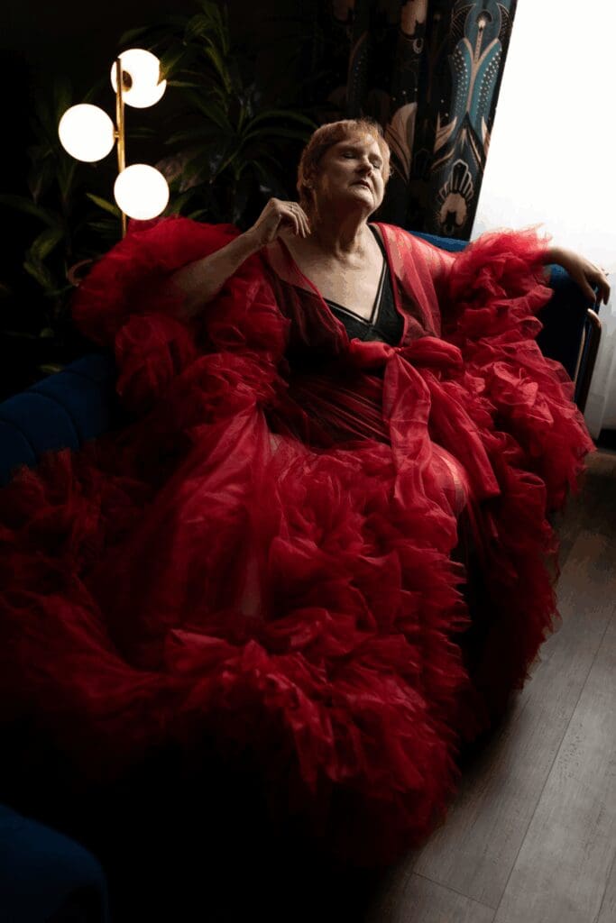 Woman in a dramatic red robe posing on a blue couch during a boudoir photography session in Sioux Falls, South Dakota